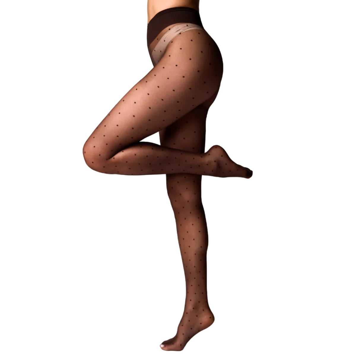 A model's legs wearing sheer brown polka-dot tights, shown from the waist down in a yoga tree pose against a white studio background.