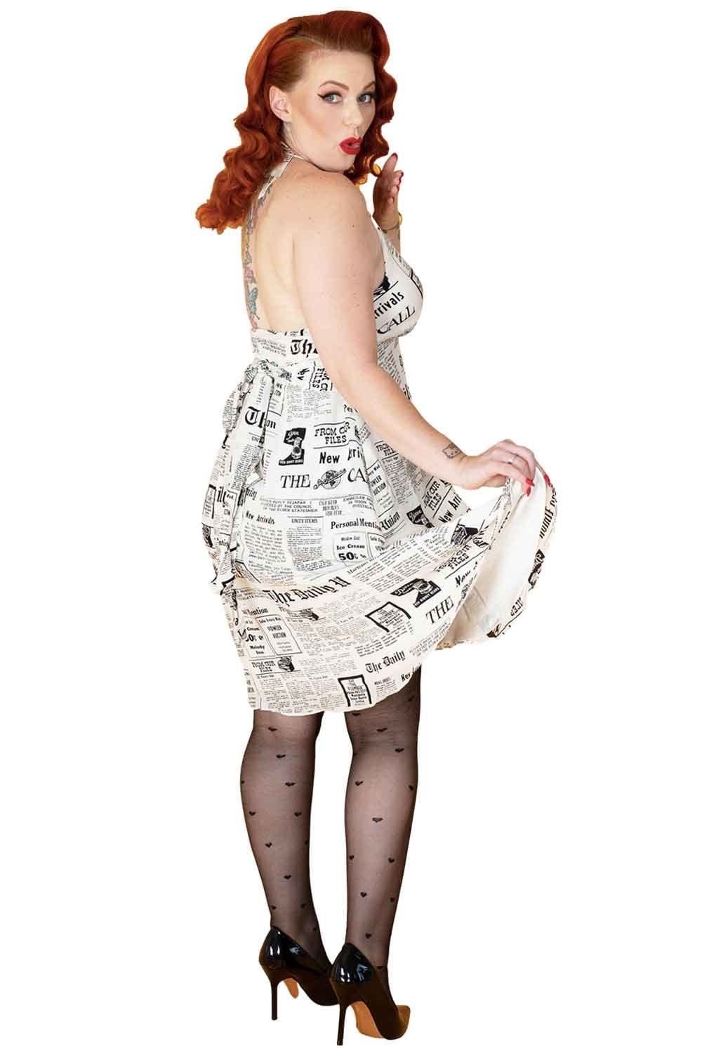 Woman wearing a dress made of newspaper  and black all over heart tights on a white background