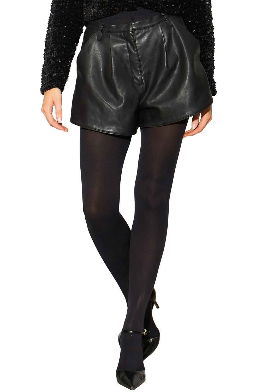 Model wearing black leather shorts and black opaque tights on a white background