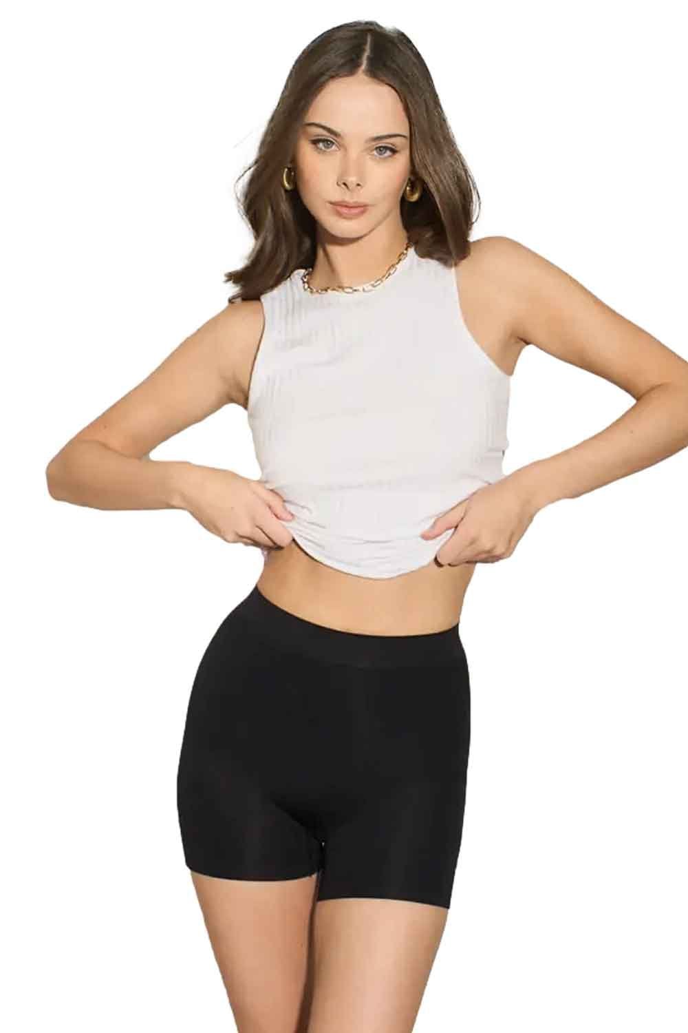 Model wearing a white sleeveless top and black shapewear shorts on a white background