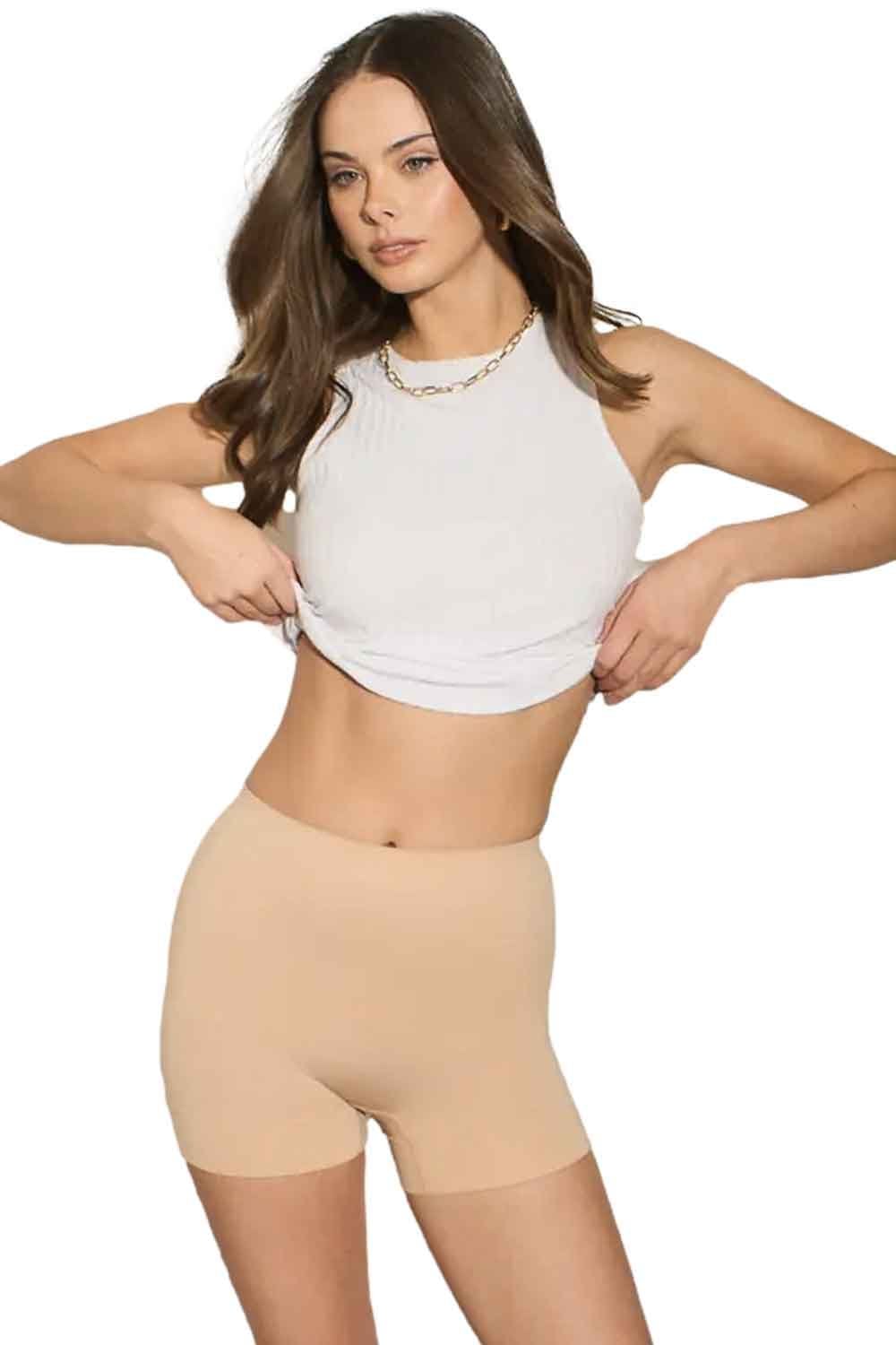 Model wearing a white crop top and nude shapewear shorts on a white background