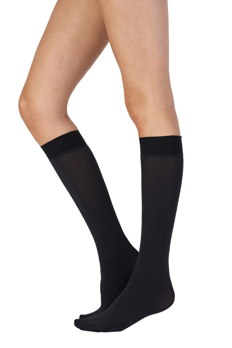 Black knee-high socks worn by a person on a white background