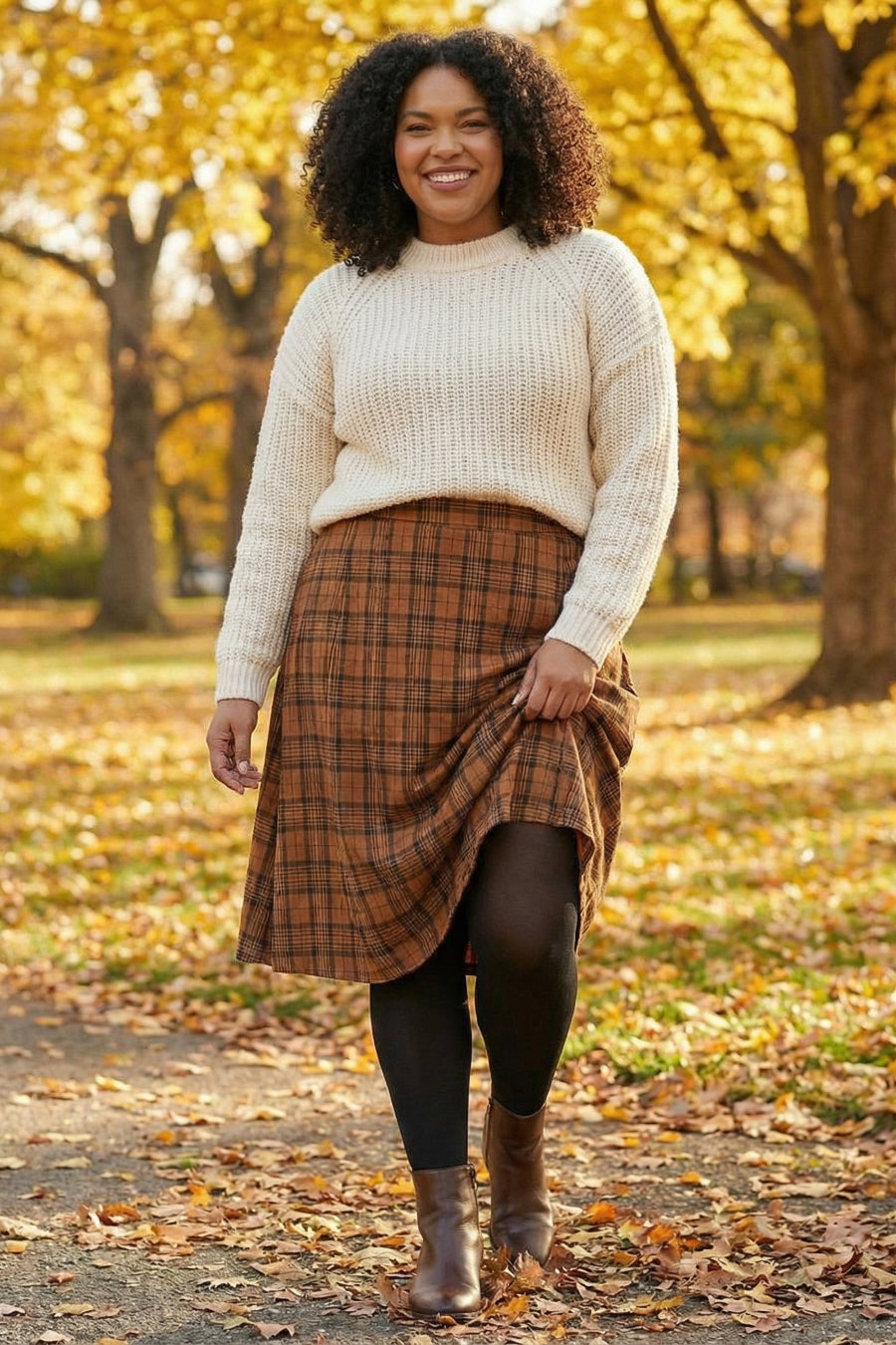 Woman in a white sweater, plaid skirt and tights standing in an autumn park.