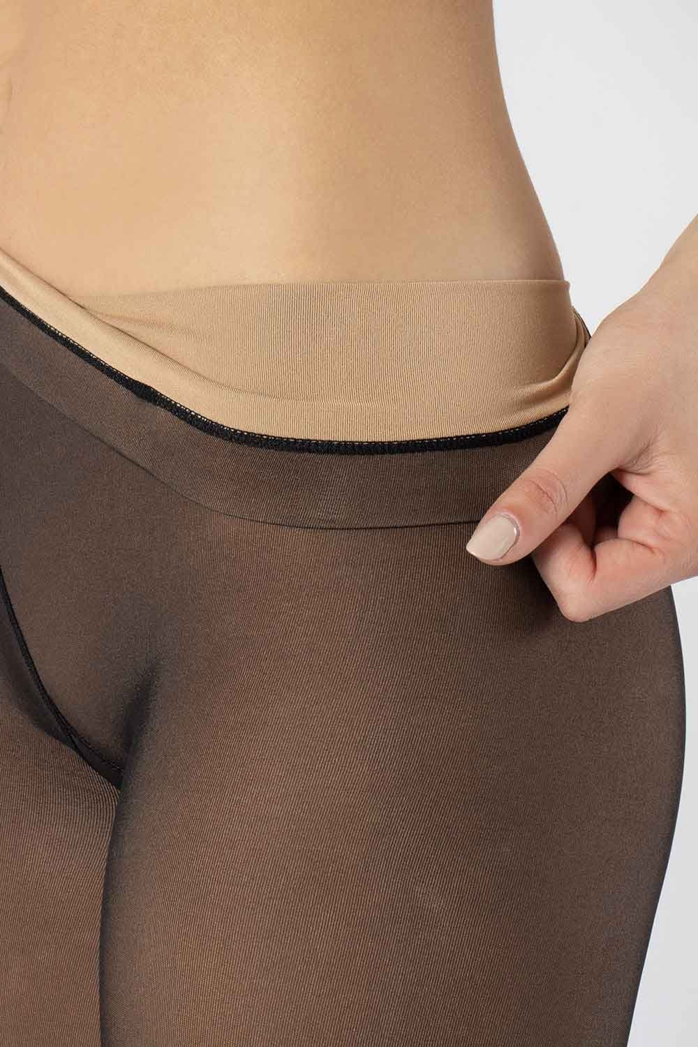 Close-up of  Cette sheer appearance 80 denier tights with a hand adjusting the waistband against a white background