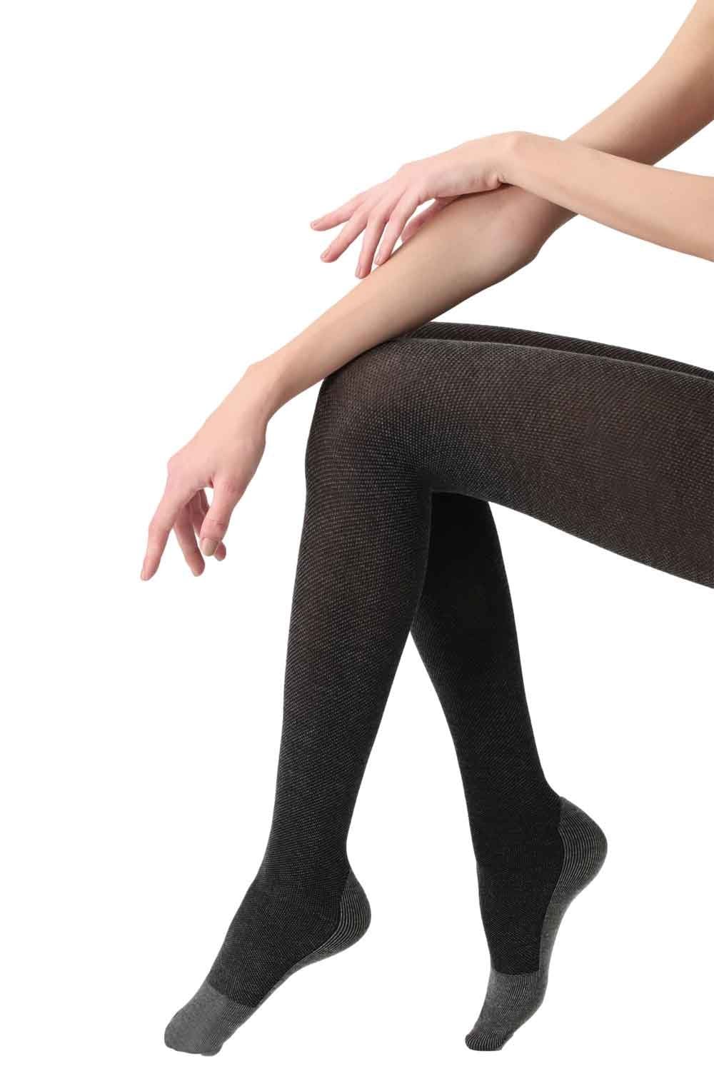 Person wearing gray piquet patterned tights sitting on a white background