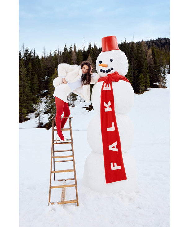 Person on a ladder building a snowman with a red scarf in a snowy landscape wearing falke red scarlet tights
