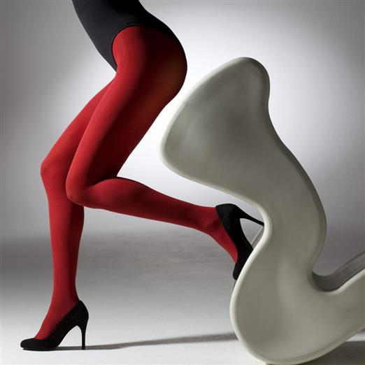 Person wearing red tights and black high heels standing next to a white chair on a gray background