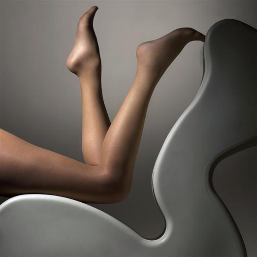 Legs wearing tights on a modern chair against a grey background