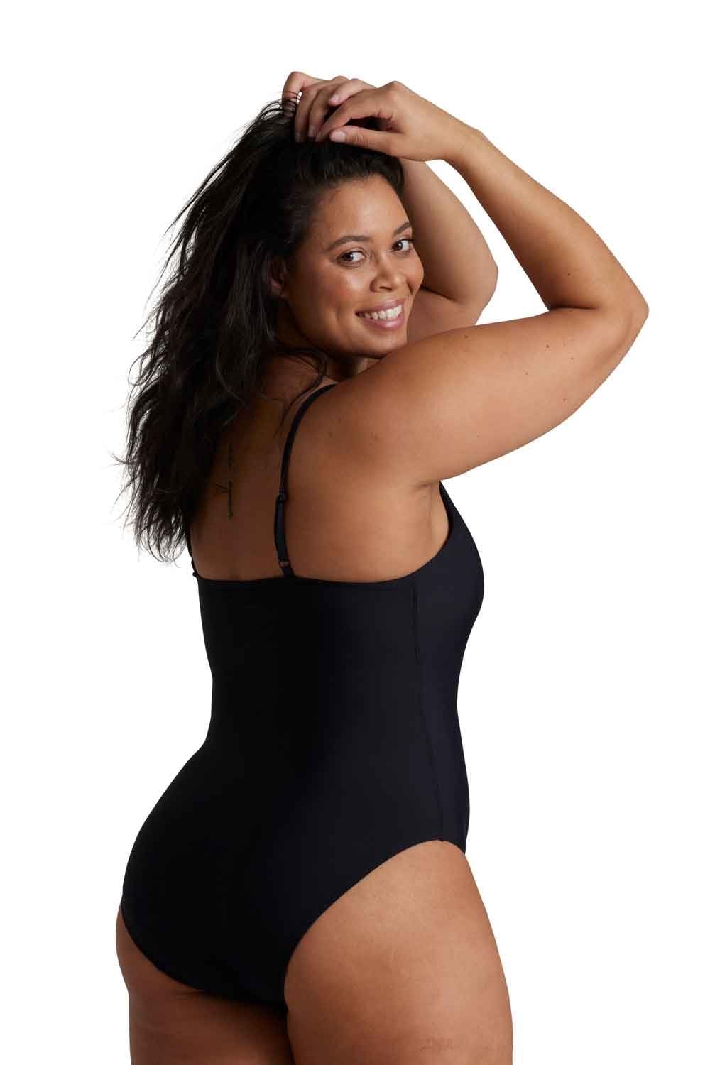 Woman wearing a black love luna period  one piece swimsuit against a white background