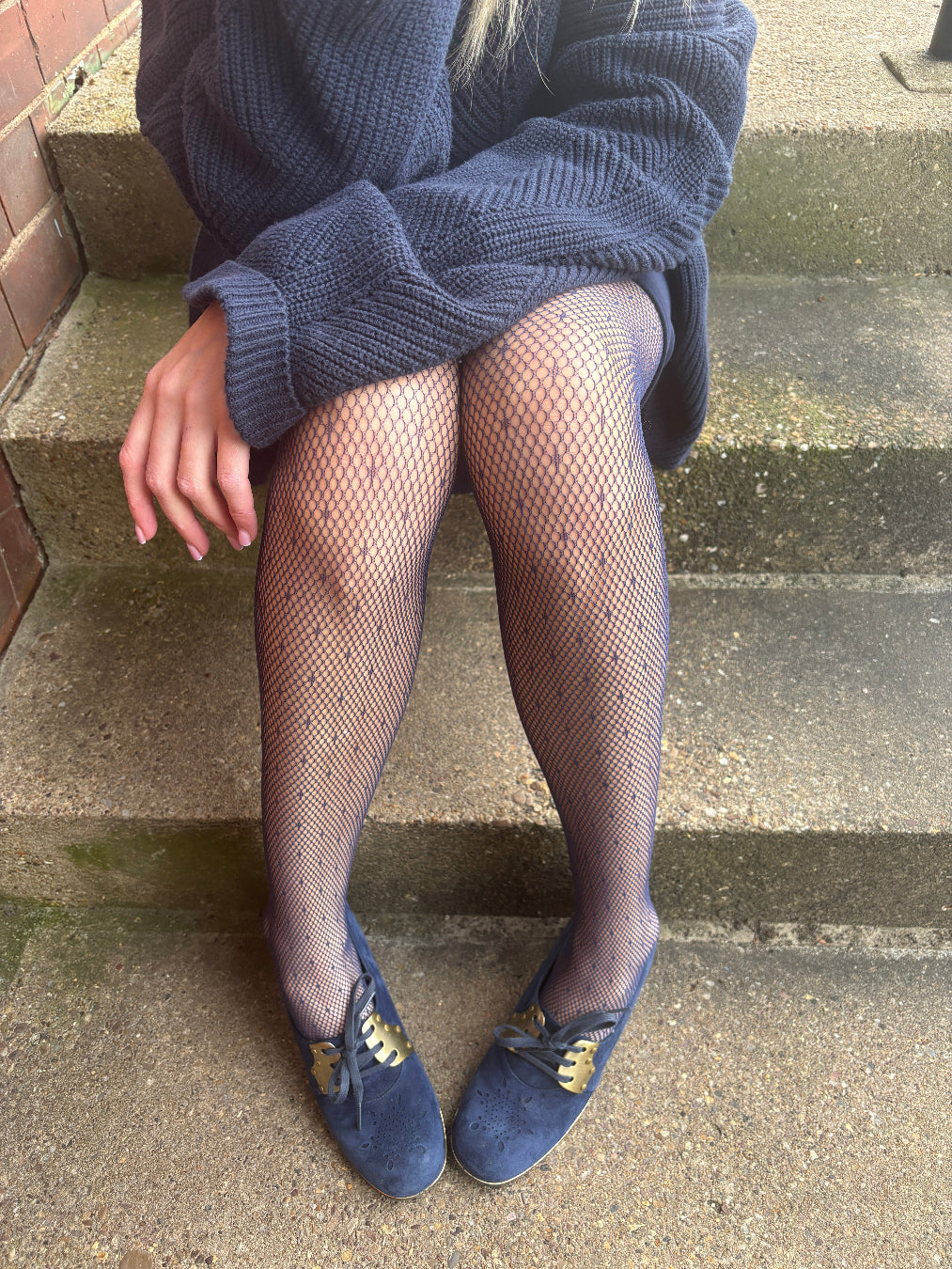 Person wearing navy fishnet tights and blue shoes.