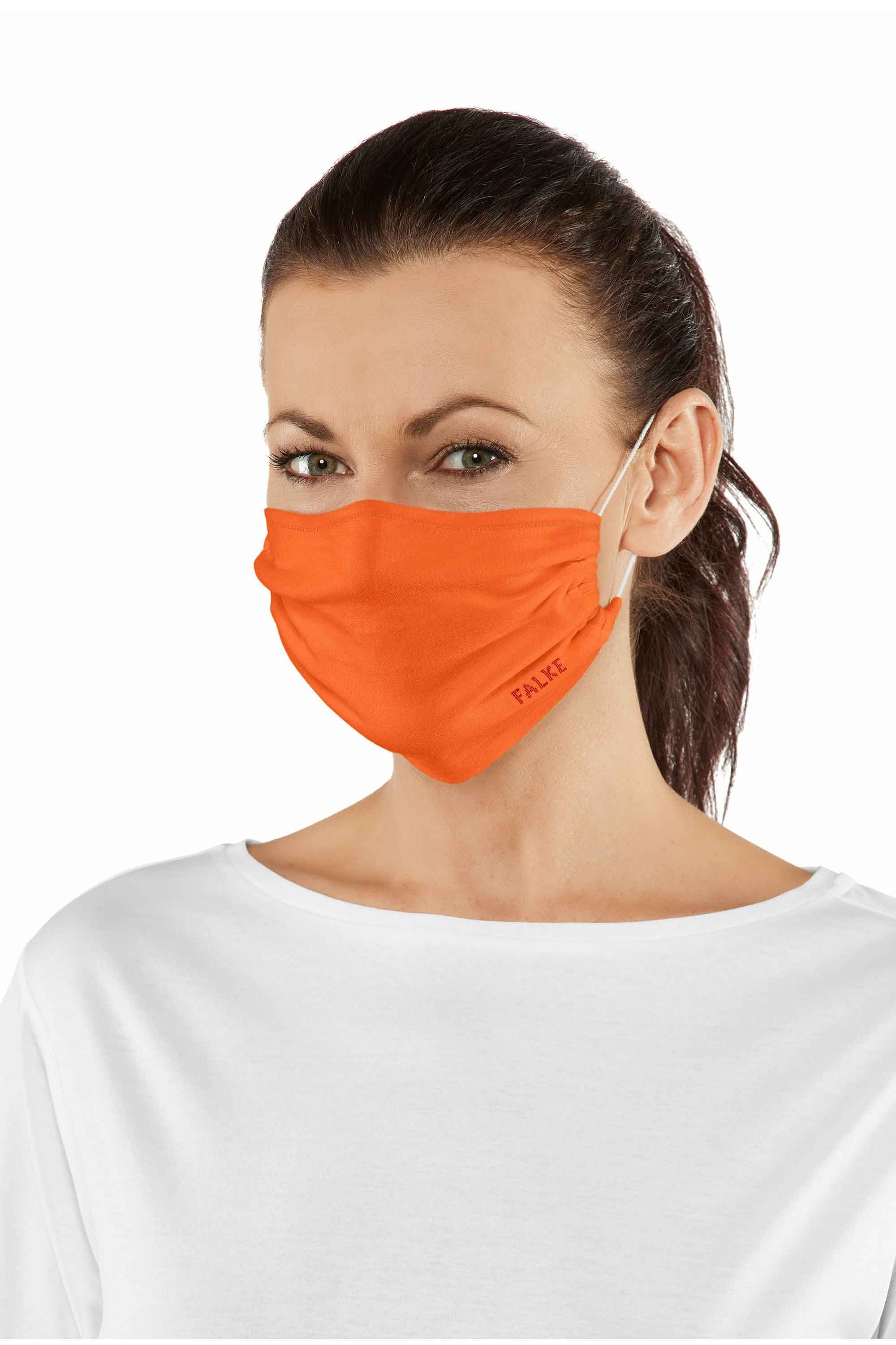 Woman wearing an orange face mask with a visible brand logo on a white background
