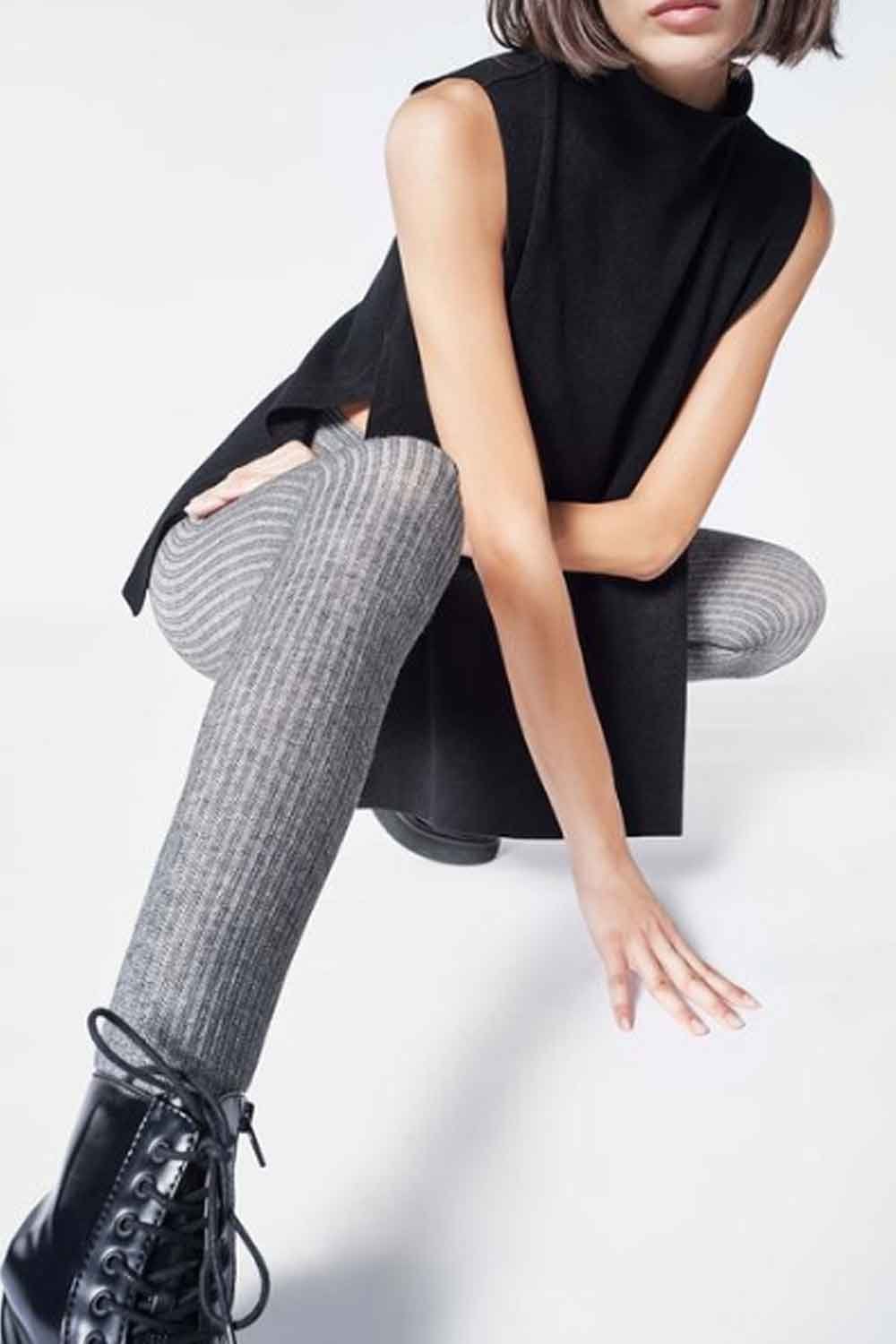 Person wearing a black sleeveless top and gray ribbed eco tights  on a white background