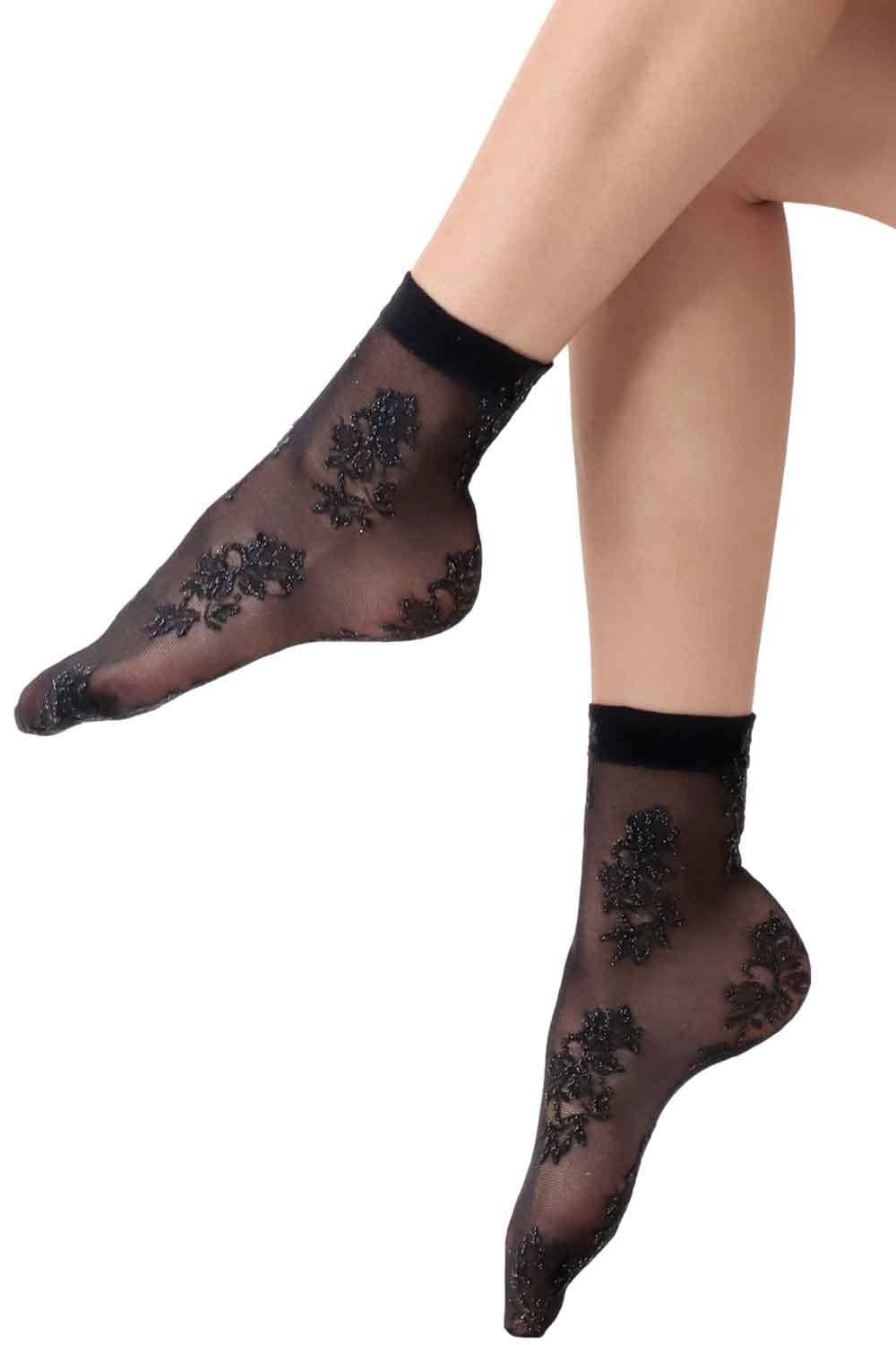 Black sheer socks with floral lace design worn by a person on a white background