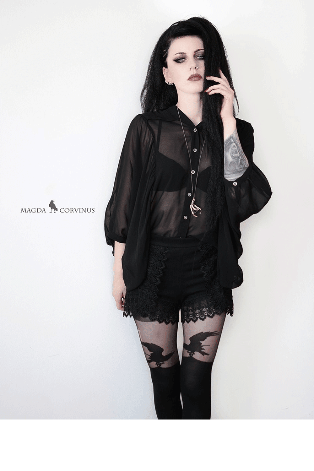 Person wearing a black outfit with over the knee patterned raven tights  on a white background
