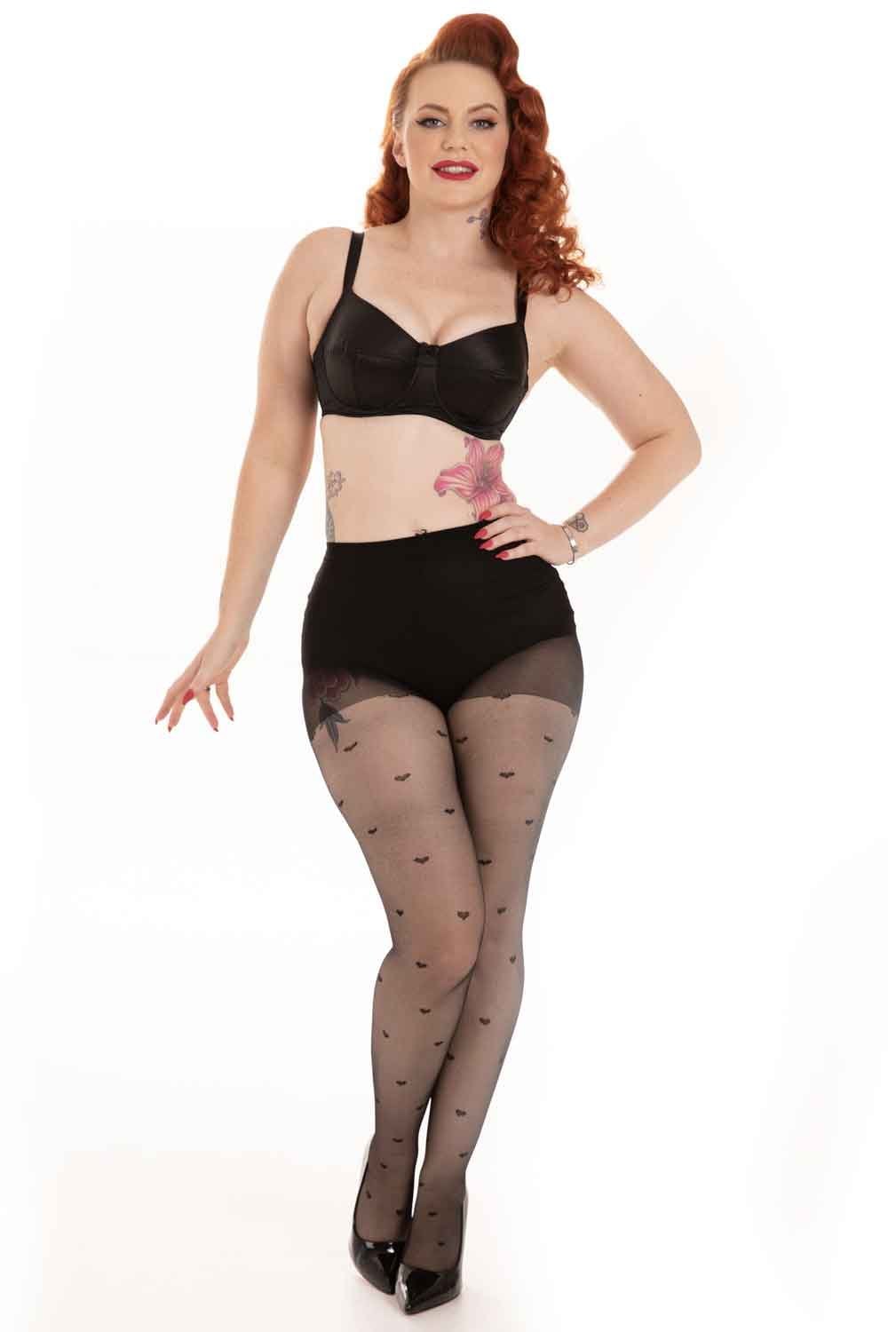 Woman wearing a black bra and all over black heart tights  on a white background