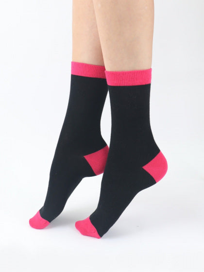 Black socks with pink accents worn by a person on a white background