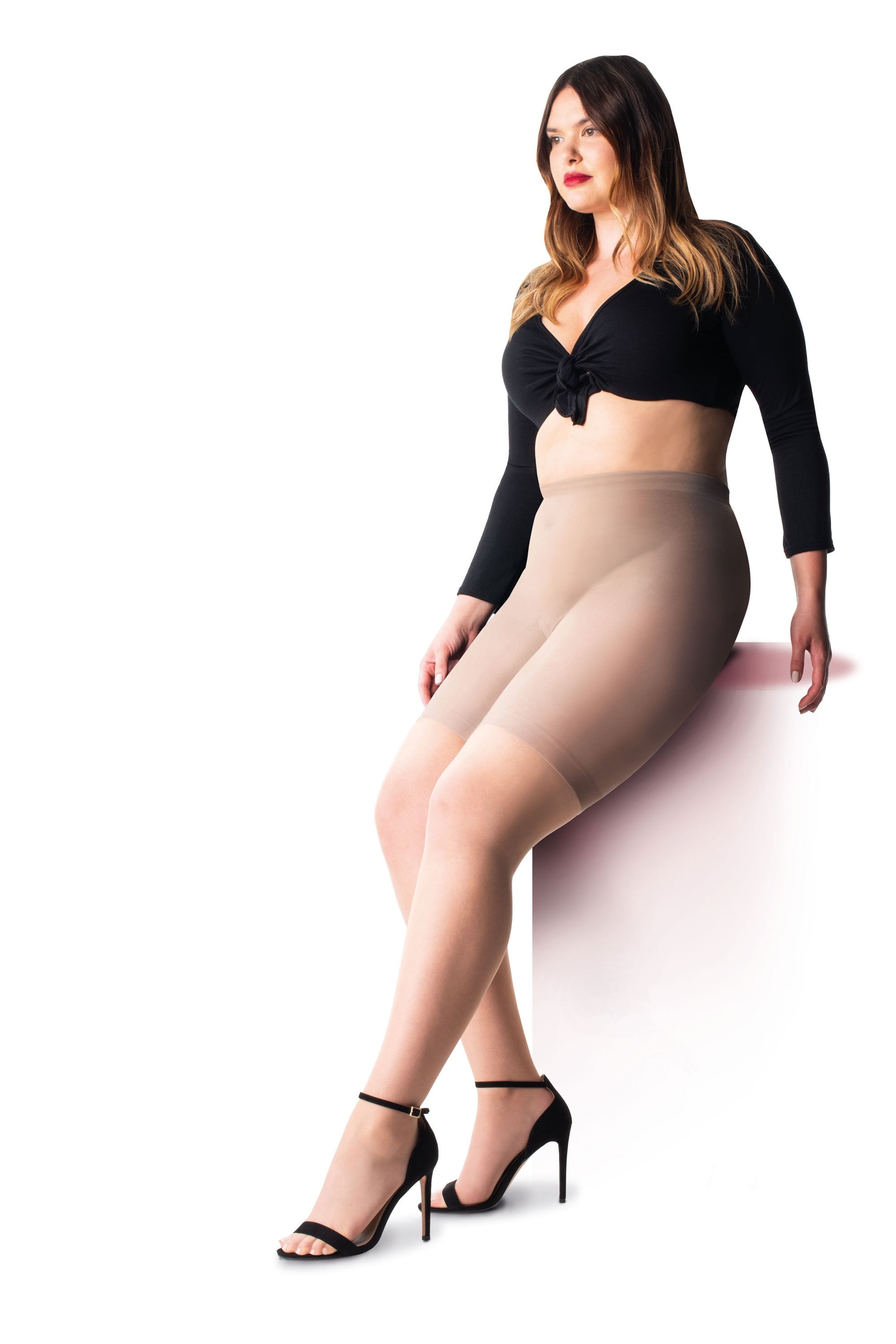 Woman wearing nude cooling shorts and a black top on a white background