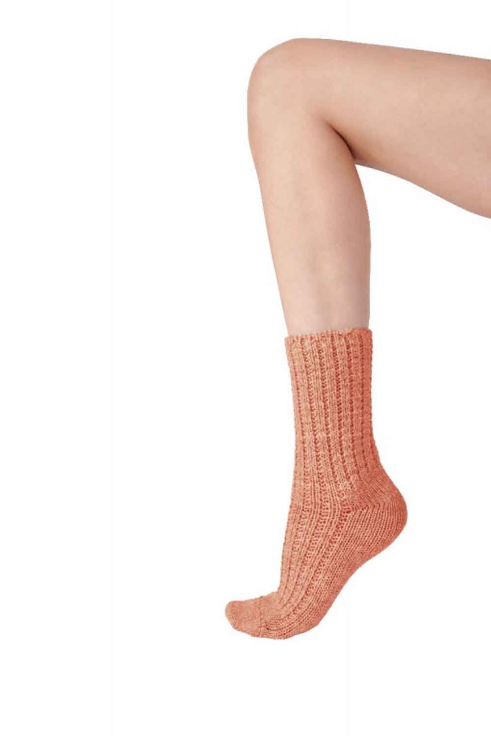 Person wearing a coral knitted sock on a white background