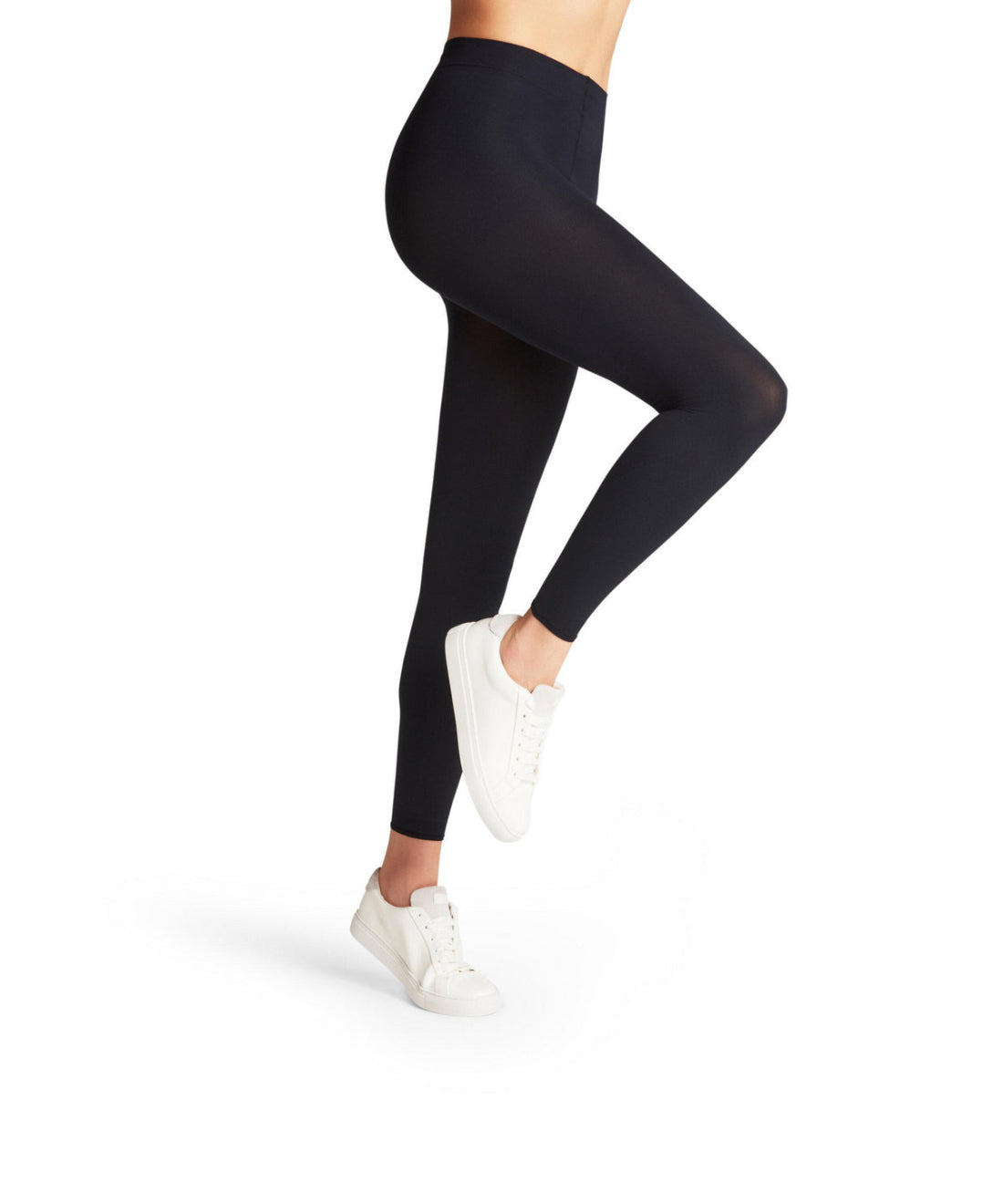 Person wearing navy leggings and white sneakers on a white background