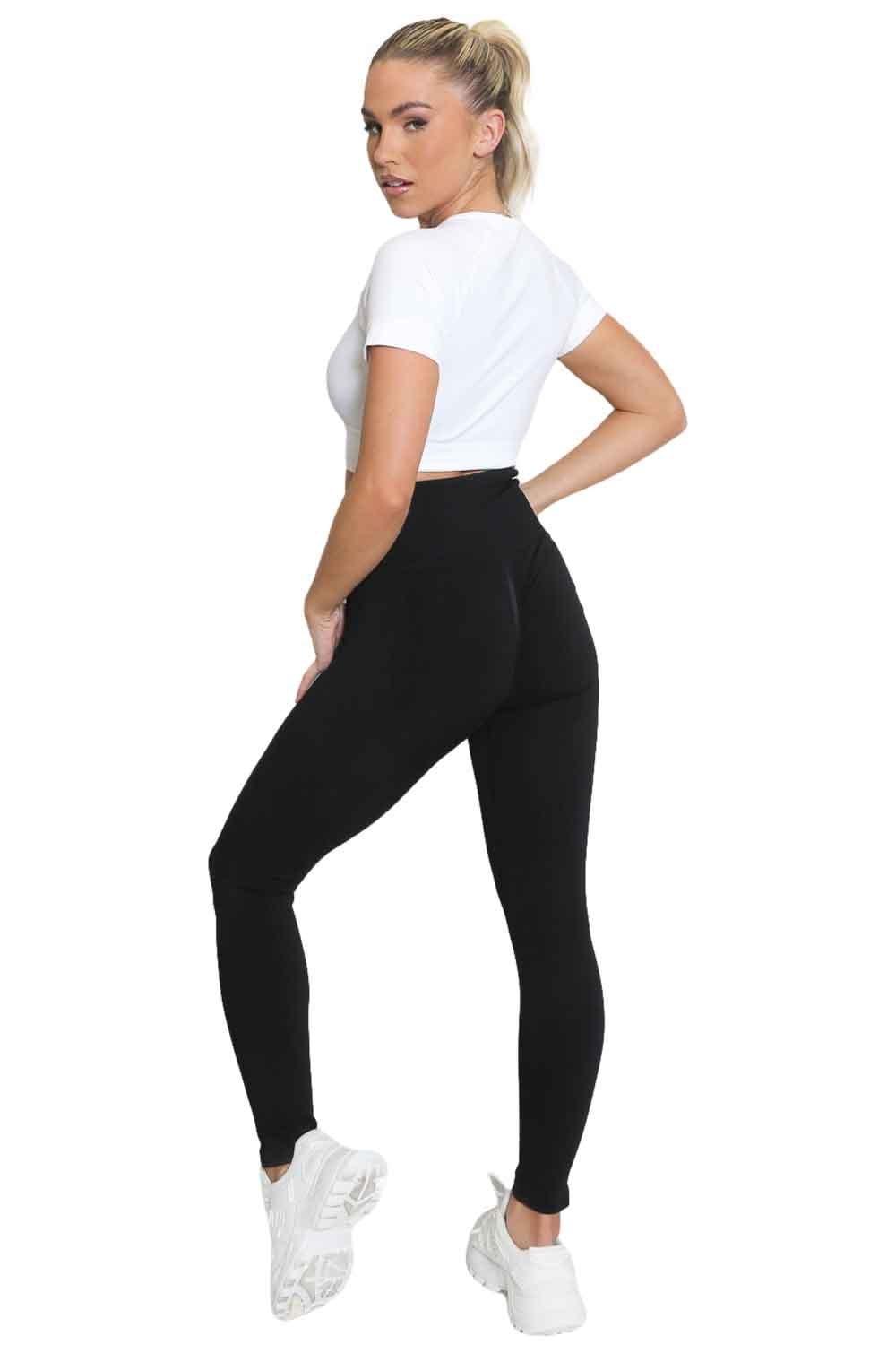 Model wearing black leggings and a white crop top on a white background