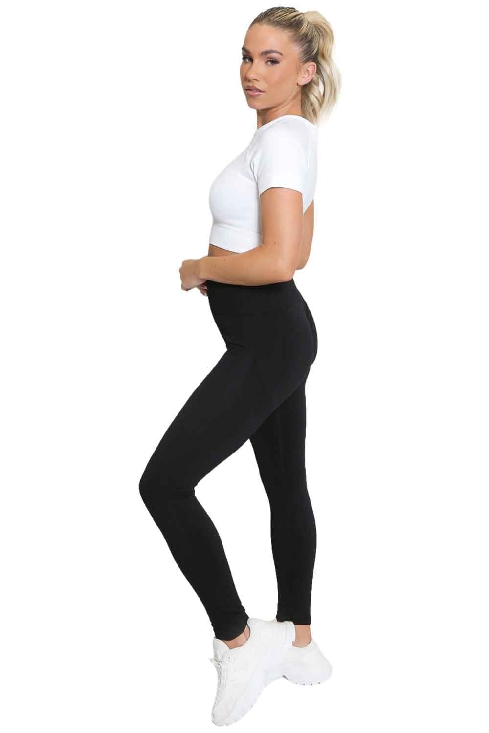Model wearing a white crop top and black leggings on a white background