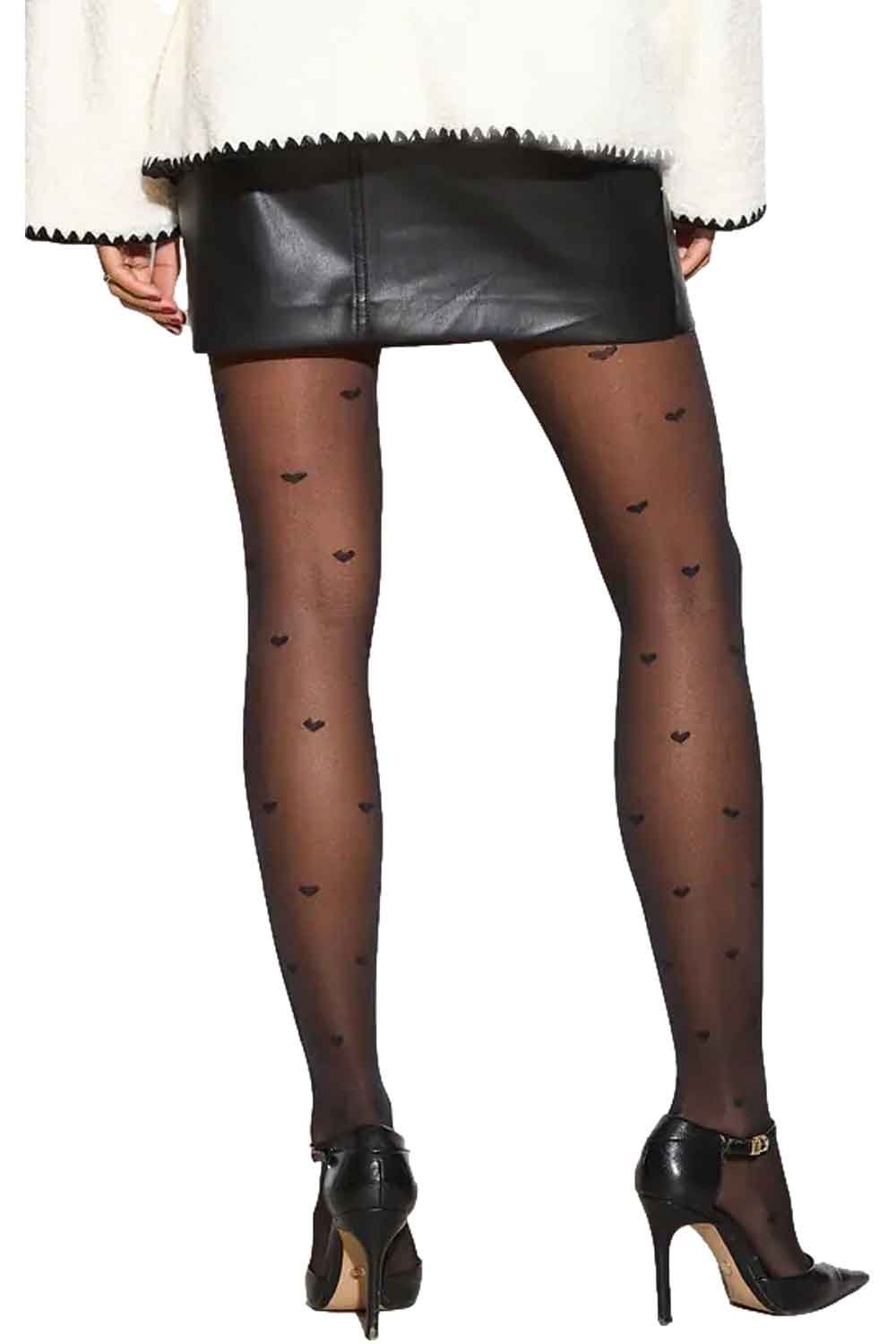 Black heart-patterned tights worn with a white sweater and black leather skirt on a white background.