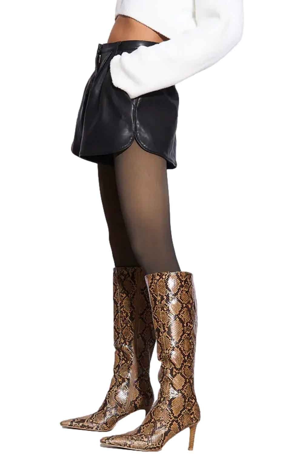 Model wearing black leather skirt, sheer fleece lined  tights, and snake print knee-high boots on a white background