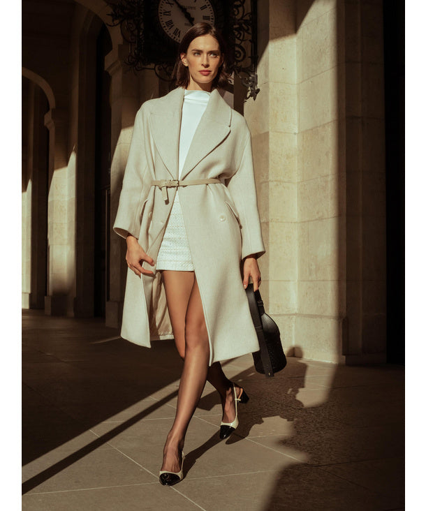 Woman wearing sheer black tights and  a long coat walking in an architectural setting