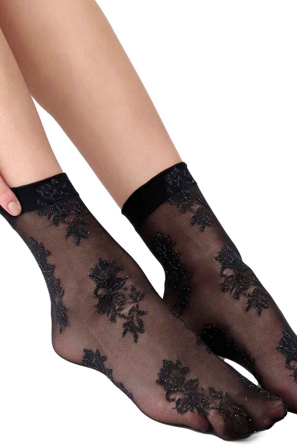 Black sheer socks with floral lace details worn by a person on a white background