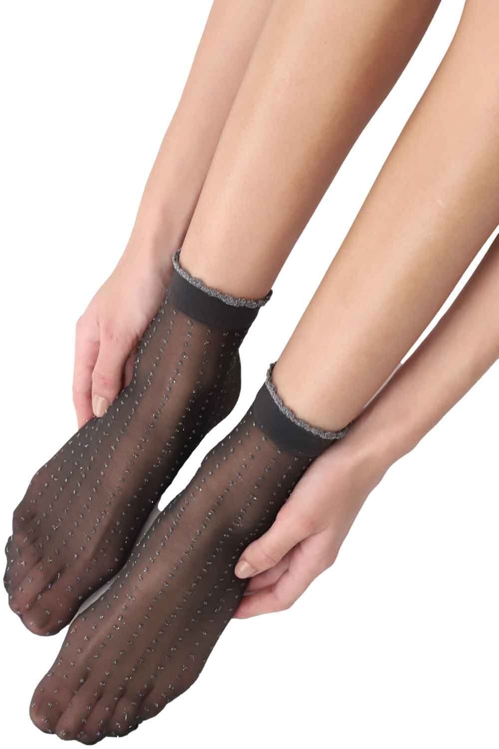 Black/gold glitter dot socks worn by a person on a white background
