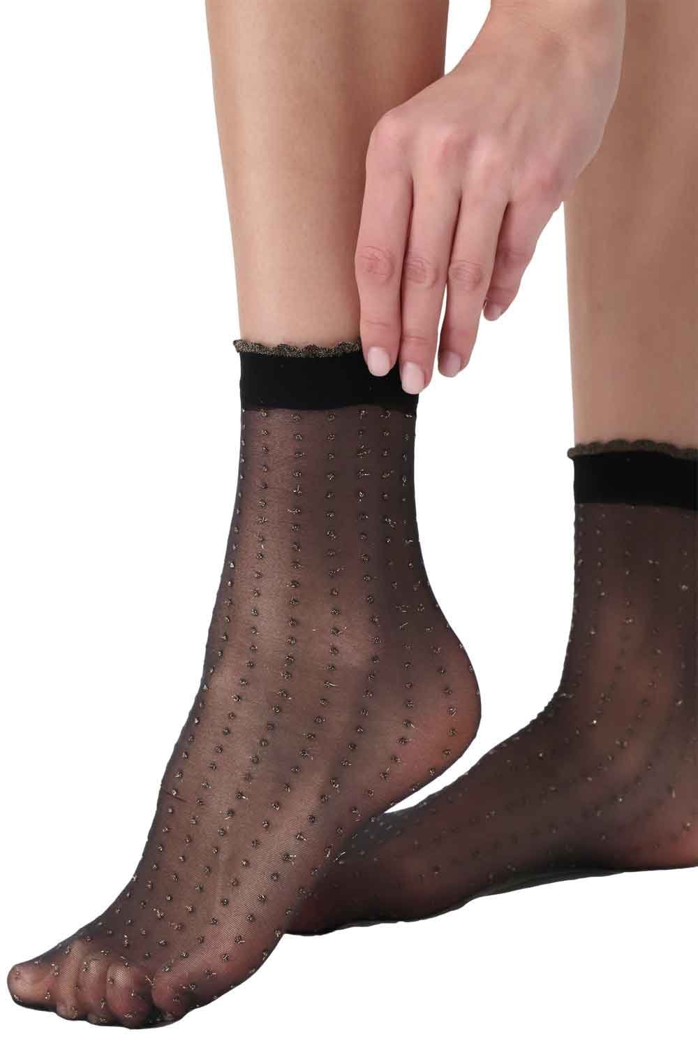 Black/gold glitter  socks with dot pattern worn by a person on a white background
