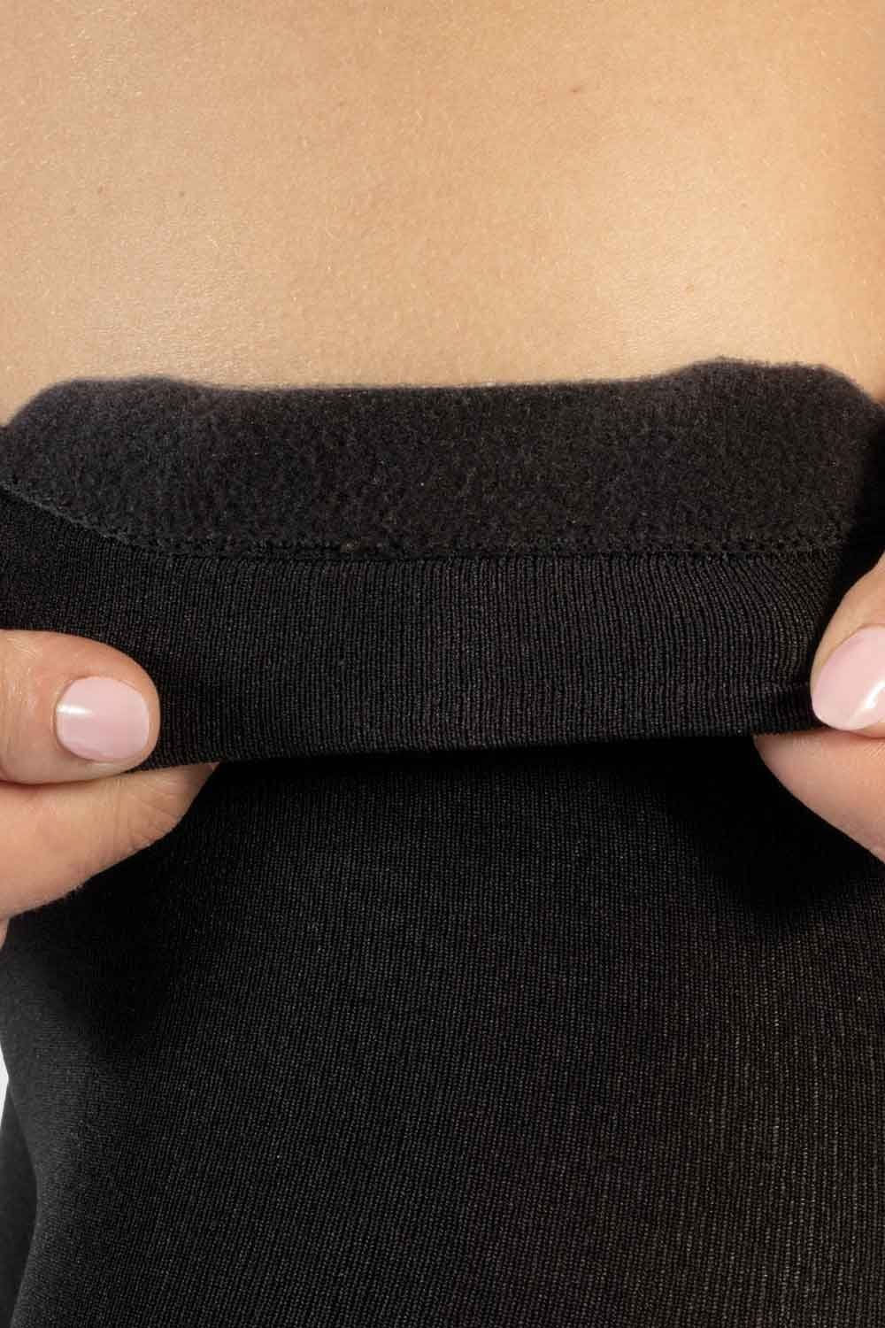 Close-up of a person holding the waistband  of the fleece lined tights  