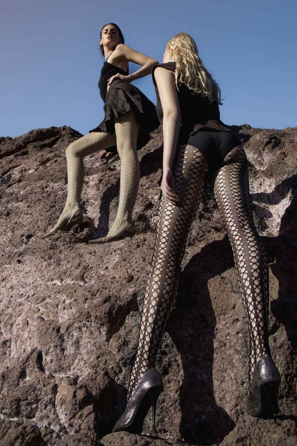 Two women sitting on a rocky surface wearing geometric patterned tights