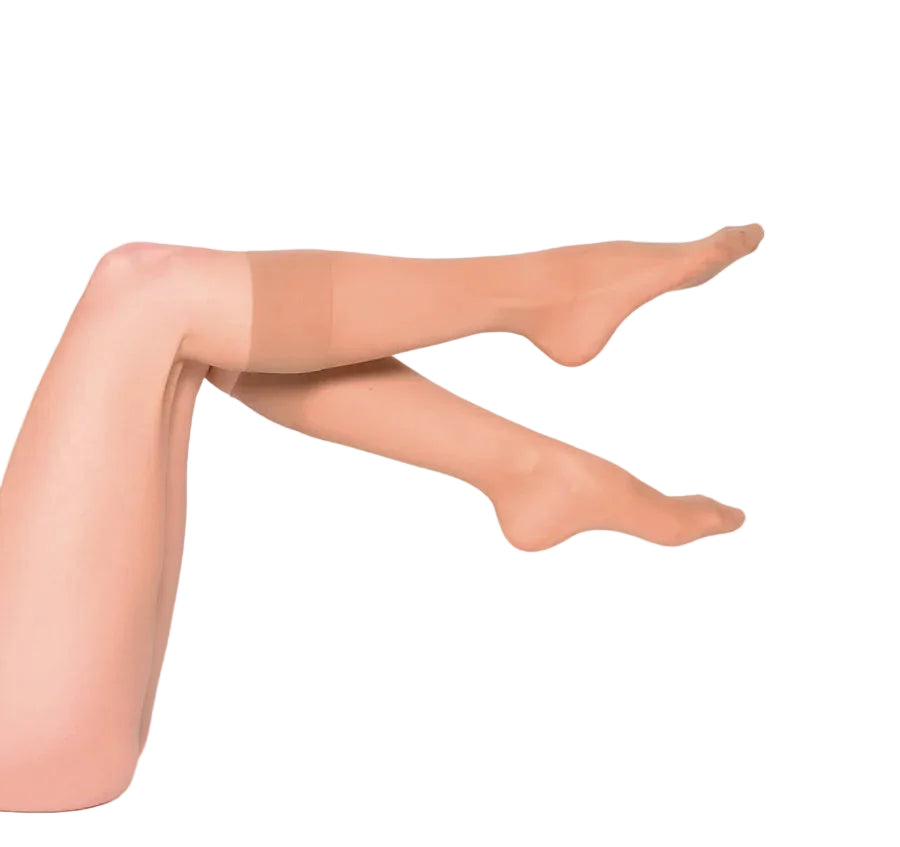 A pair of sheer nude knee highs worn on crossed legs, photographed against a white studio background.