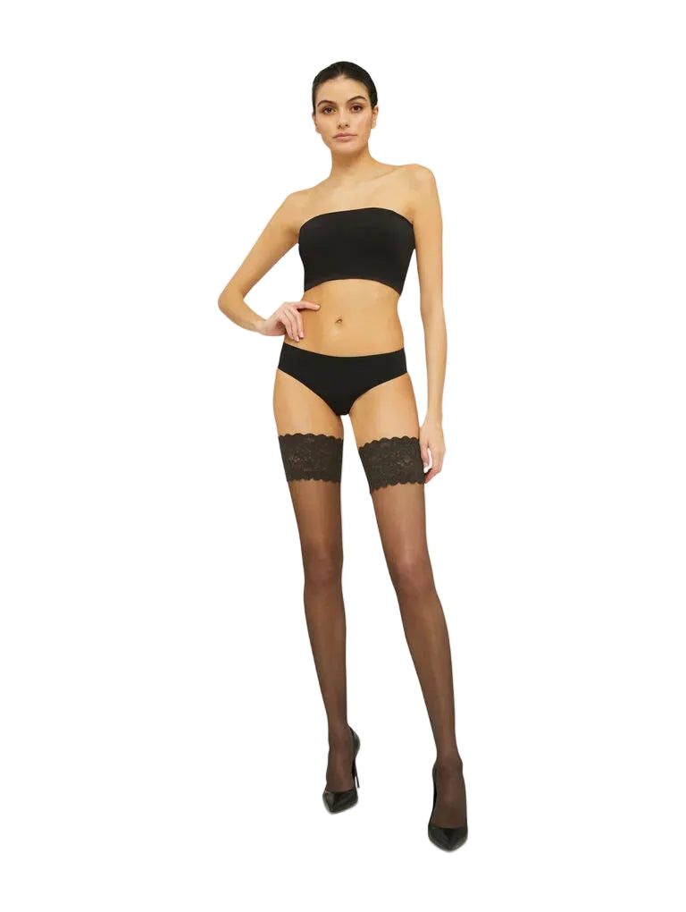 Woman wearing black lingerie set with hold ups on a white background