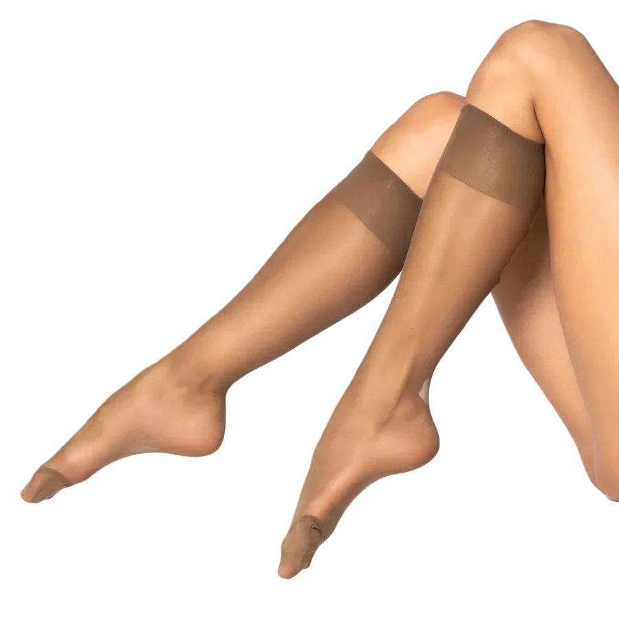 A close-up of a model's legs wearing sheer brown knee highs against a white studio background.